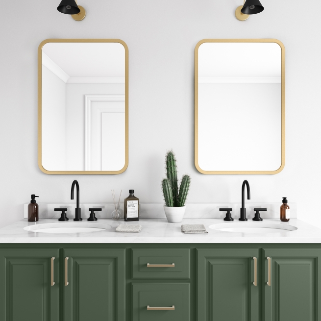 Matte gold rubber framed rectangle mirror hanging on bathroom wall above forest green vanity