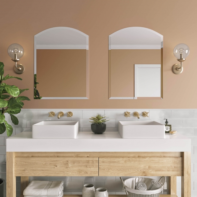 Frameless beveled arch-top mirrors hanging on bathroom wall above double sink vanity