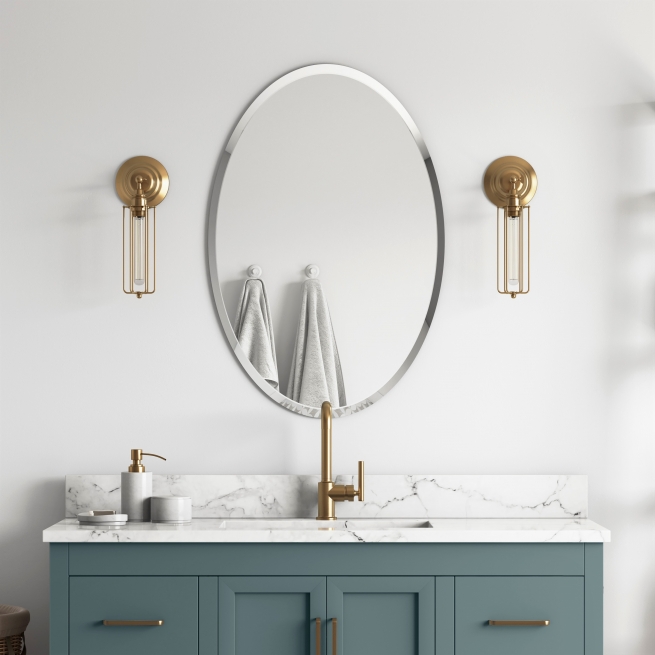 Frameless beveled oval mirror hanging on bathroom wall above muted teal vanity