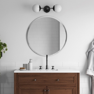 Frameless beveled round mirror hanging on bathroom wall above wood vanity