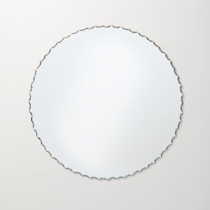 Frameless chiseled edge round mirror hanging on beige wall