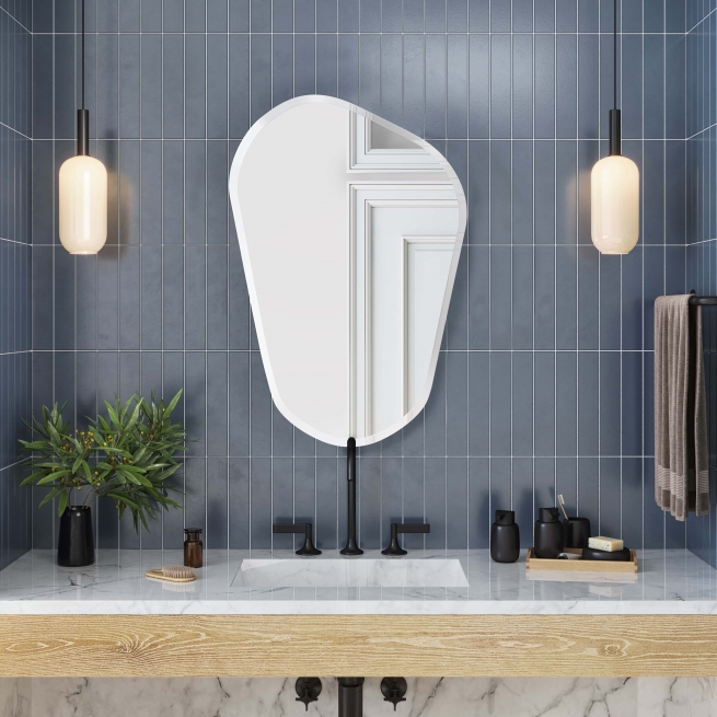 Frameless beveled asymmetrical novelty mirror hanging on blue tiled bathroom wall above vanity