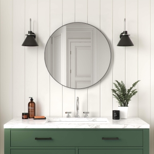 Black metal framed round mirror hanging on bathroom wall above single sink vanity