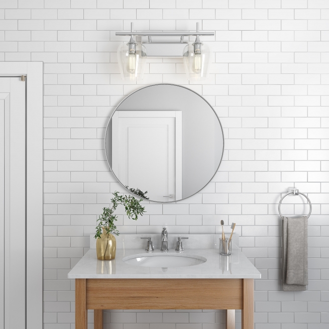 Silver metal framed round mirror hanging on bathroom wall above single sink vanity