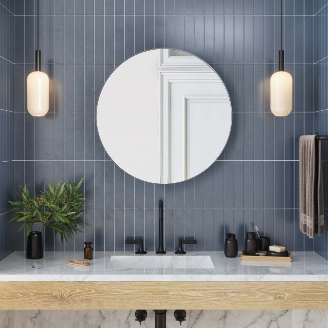 White metal framed round mirror hanging on bathroom wall above single sink vanity