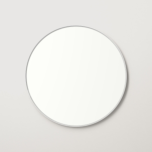 White metal framed round mirror hanging on beige wall