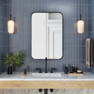 Black metal framed rounded rectangle mirror hanging on bathroom wall above single sink vanity