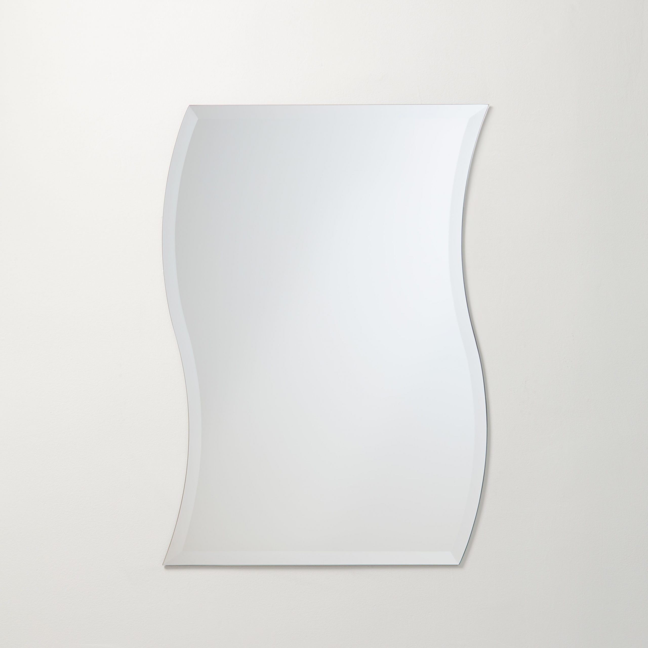 Frameless beveled wave/swerve mirror hanging on beige wall