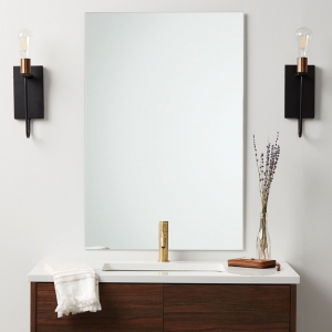 Frameless polished edge rectangle mirror hanging on bathroom wall above single sink wood vanity