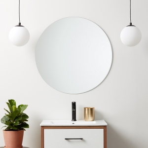 Polished edge round mirror hanging on bathroom wall above single sink vanity