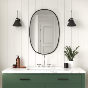 Black rubber framed oval mirror hanging on bathroom wall above green vanity