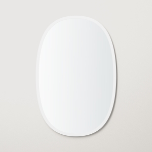 White rubber framed oval mirror hanging on beige wall