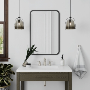 Black rubber framed rectangle mirror hanging on bathroom wall above single sink vanity