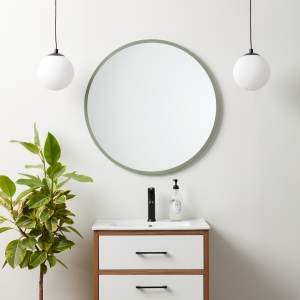 Sage green rubber framed round mirror hanging on bathroom wall above vanity