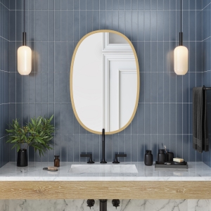 Matte gold rubber framed oval mirror hanging on bathroom tile wall above vanity